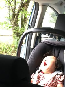 車のベビーシートであくびする赤ちゃん